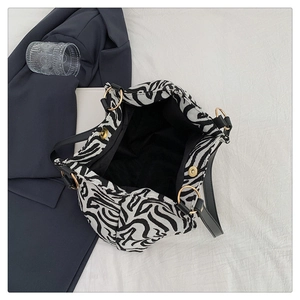 Detailed top view of large zebra print tote bag with gold magnetic closure and black lining