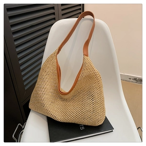 Detail of beige woven tote bag showing raffia texture and brown faux leather shoulder strap
