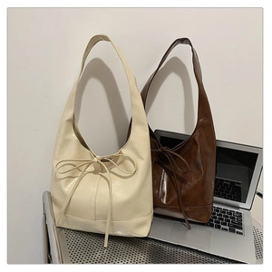 Detail view of cream and brown PU leather tote bags with bow decoration in office setting
