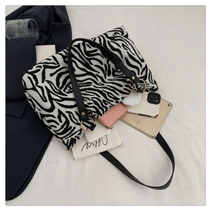 Flat lay of zebra print tote bag filled with office essentials like tablet and phone