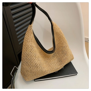 Detail of hollow-out woven pattern on straw tote bag with black faux leather trim