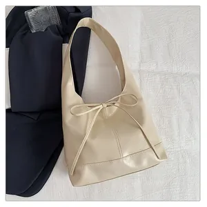 Detail of cream faux leather tote bag with a minimalist bow and wide shoulder strap