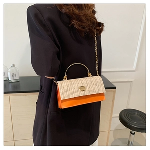Détail du sac bandoulière en paille tissée et cuir orange avec poignée dorée sur modèle