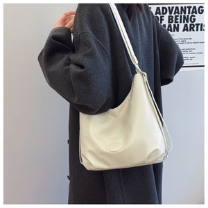 Detail of a large cream shoulder bag showing the embossed logo and adjustable strap