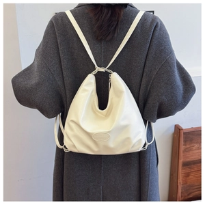 Detail of white soft leather shoulder bag with U-shaped silhouette on dark coat