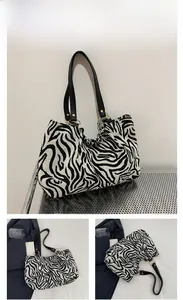 Detail of large zebra print tote bag with black handles and golden metal ring accents