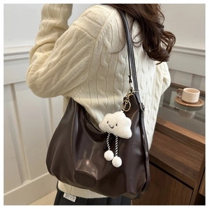Close-up of a dark brown hobo tote bag in soft PU leather with a cute cloud plush charm