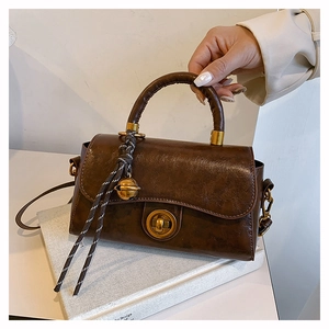 Detail of vintage brown tote bag with brass twist lock and woven tassel charm