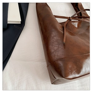 Detail of dark brown tote bag showing oil-wax texture and drawstring closure