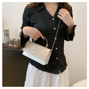 Détail du sac en paille tissée avec garniture en cuir blanc et anse ronde dorée