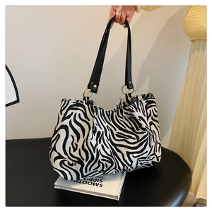 Detail of zebra pattern tote bag featuring gold rings and black leather straps