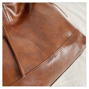 Close-up of deep brown oil-wax leather tote bag with refined stitching and shiny texture