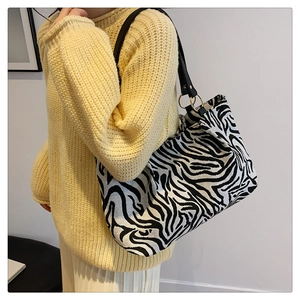 Close-up of large zebra print tote bag with black leather straps and gold metal rings