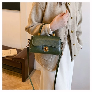 Detail of dark green oil wax leather handbag with vintage gold clasp and top handle strap
