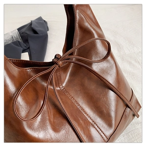 Detailed view of dark brown vintage faux leather tote with decorative ribbon bow