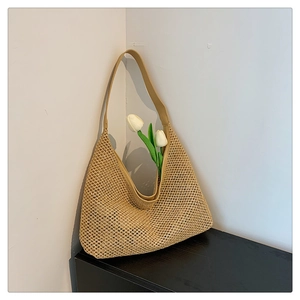 Detail of hollow woven straw tote bag featuring beige texture and faux leather shoulder strap