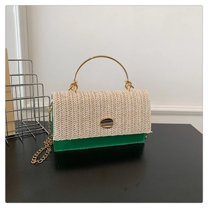 Detail of green leather and beige straw patchwork handbag with gold metal hardware