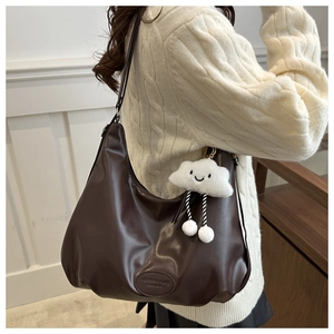 Dark brown large PU leather tote bag with white cloud plush charm in casual side-carry view