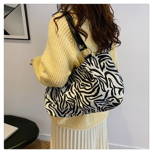 Detail of zebra print canvas bag with black strap and golden metal ring hardware