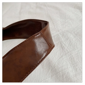 Detailed close-up of dark brown leather shoulder strap with premium stitching on tote bag