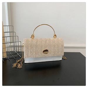 Detail of woven straw and white leather handbag with gold metal ring handle and chain