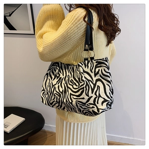 Detail of zebra print canvas tote with black leather straps and metal ring accents