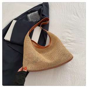Flat lay of handwoven straw tote bag with brown leather trim and natural wood tone