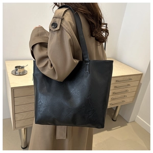 Close-up of the fine leather texture and durable strap on the black commuter tote bag
