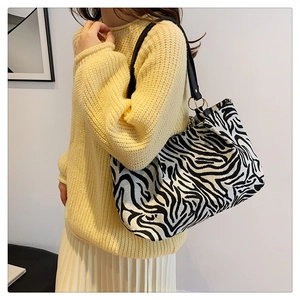 Detail view of large zebra pattern canvas tote with black leather strap on a model