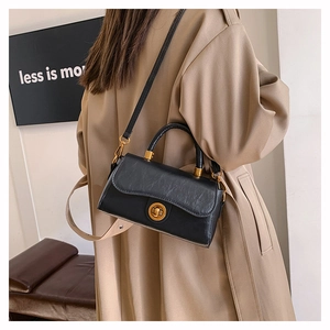 Detail of a vintage black leather crossbody bag with a gold turn-lock and top handle