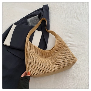 Close-up of woven straw texture and premium khaki leather shoulder strap on hobo bag