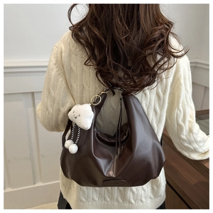 Dettaglio della borsa tote plissettata marrone scuro con charm e logo inciso