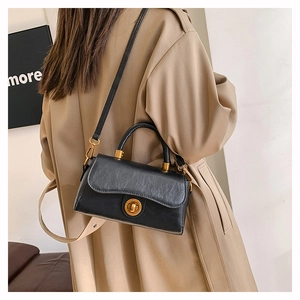 Detail of a vintage black oiled leather crossbody bag with a gold round twist lock