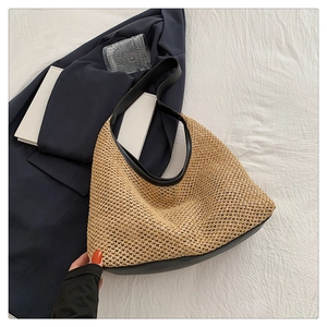 Detail of woven straw tote bag featuring black faux leather bottom and slim shoulder strap