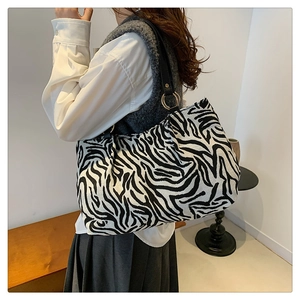 Detail of zebra pattern knit tote bag featuring a gold metal ring and leather shoulder strap