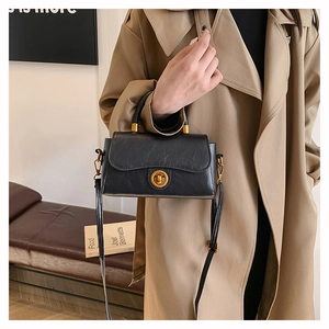 Classic black leather handbag detail featuring an elegant gold twist lock and shoulder strap