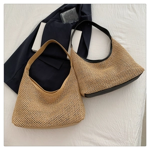 Overhead view of woven straw hobo bags in black and khaki on a white fabric background