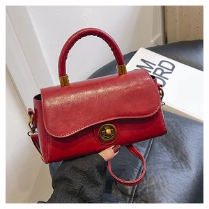 Detail of red wax leather handbag with golden twist lock and vintage polished finish