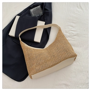 Detail of hand-woven straw tote with creamy faux leather trim and semi-moon shape silhouette