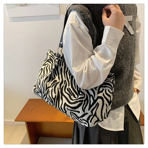 Detail of zebra pattern canvas tote with slim leather strap and gold ring connector