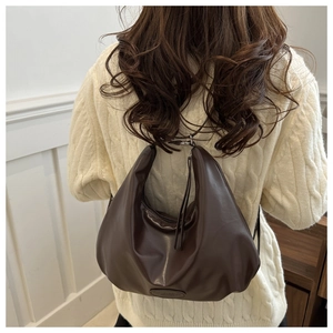 Close-up of a dark brown slouchy PU leather hobo bag worn by a model in a knit sweater
