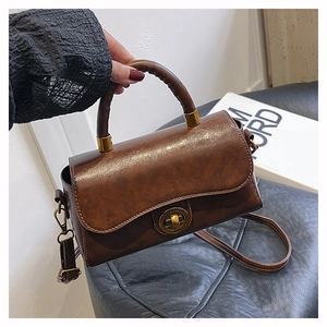 Detailed view of dark brown vintage satchel with metal lock and round handle