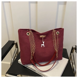 Close-up of burgundy frosted tote bag with golden chain and white deer pendant detail