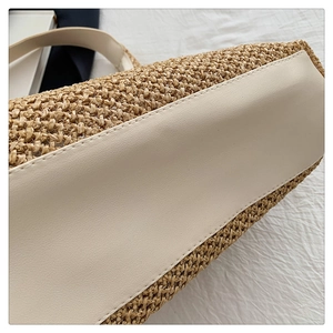 Macro detail of hand-woven straw tote bag with beige leather trim and precise stitching