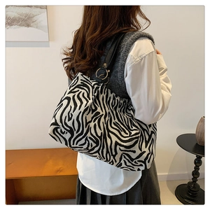 Close-up of zebra pattern tote bag featuring black leather strap and metal ring detail
