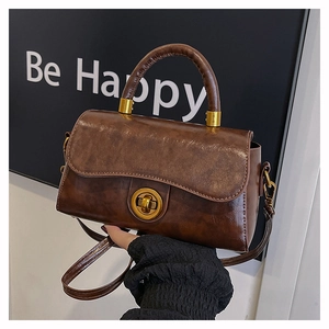 Detail of a dark brown vintage satchel with a gold ring clasp and top handle