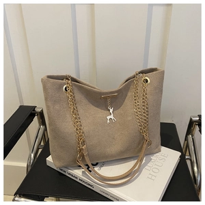 Detail of beige tote bag featuring matte leather texture and golden deer charm