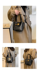 Detail of black pebbled leather bucket bag with gold triangle logo and braided rope tassel