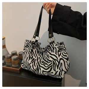 Detail of zebra print tote bag featuring black leather handles and gold metal rings