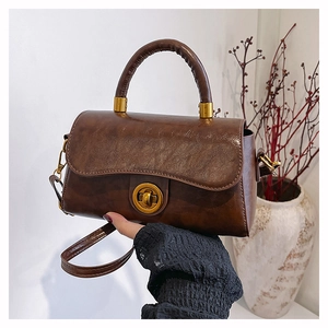 Detailed view of brown vintage leather handbag with golden round twist lock and texture